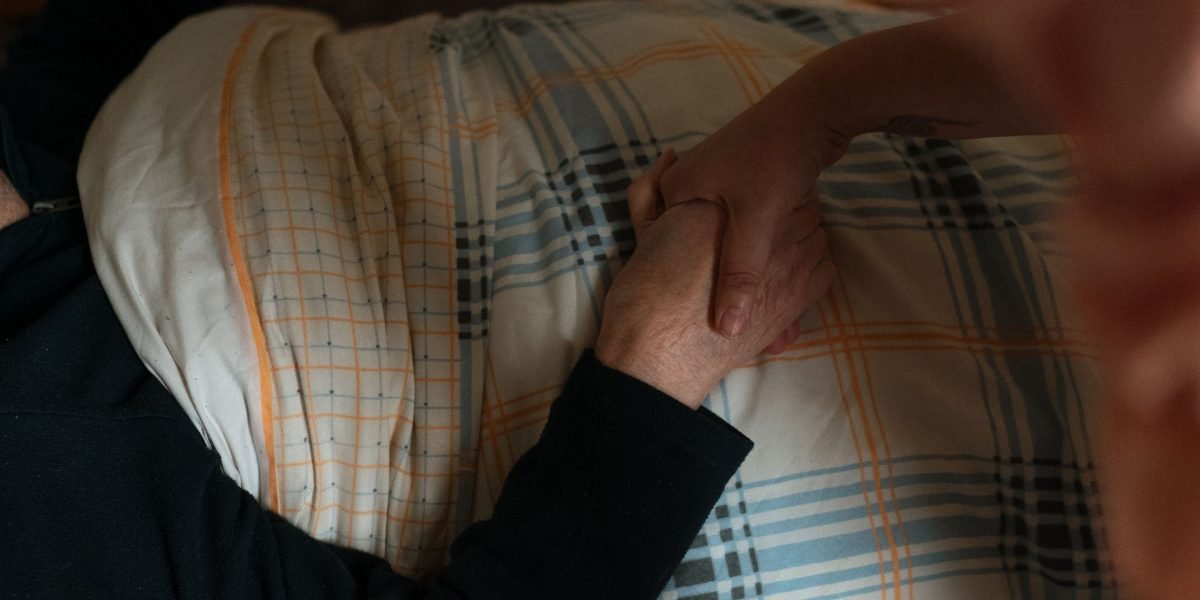 A caregiver gently assisting an elderly person in a home environment.