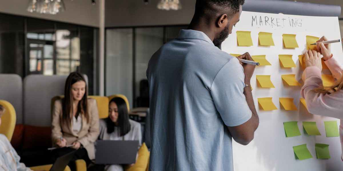 A diverse team collaborates, brainstorming ideas on a whiteboard, representing the strategic planning involved in benefit design.