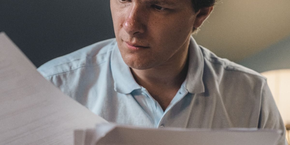 An individual thoughtfully reviewing financial documents, illustrating the careful consideration of costs and premiums for private health insurance.