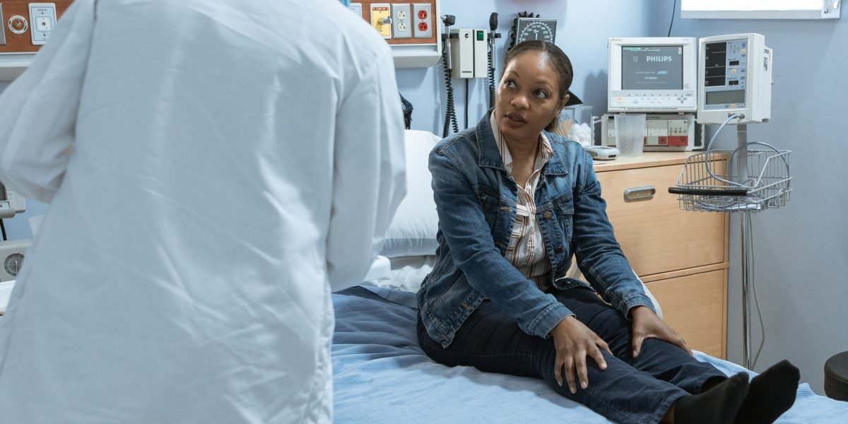 A doctor listens attentively while a patient explains their health concerns during a clinic visit.