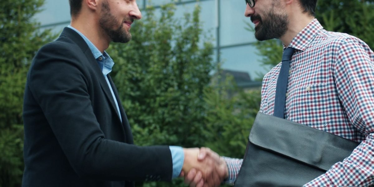 Executives from different organizations shaking hands, symbolizing a newly formed strategic partnership.