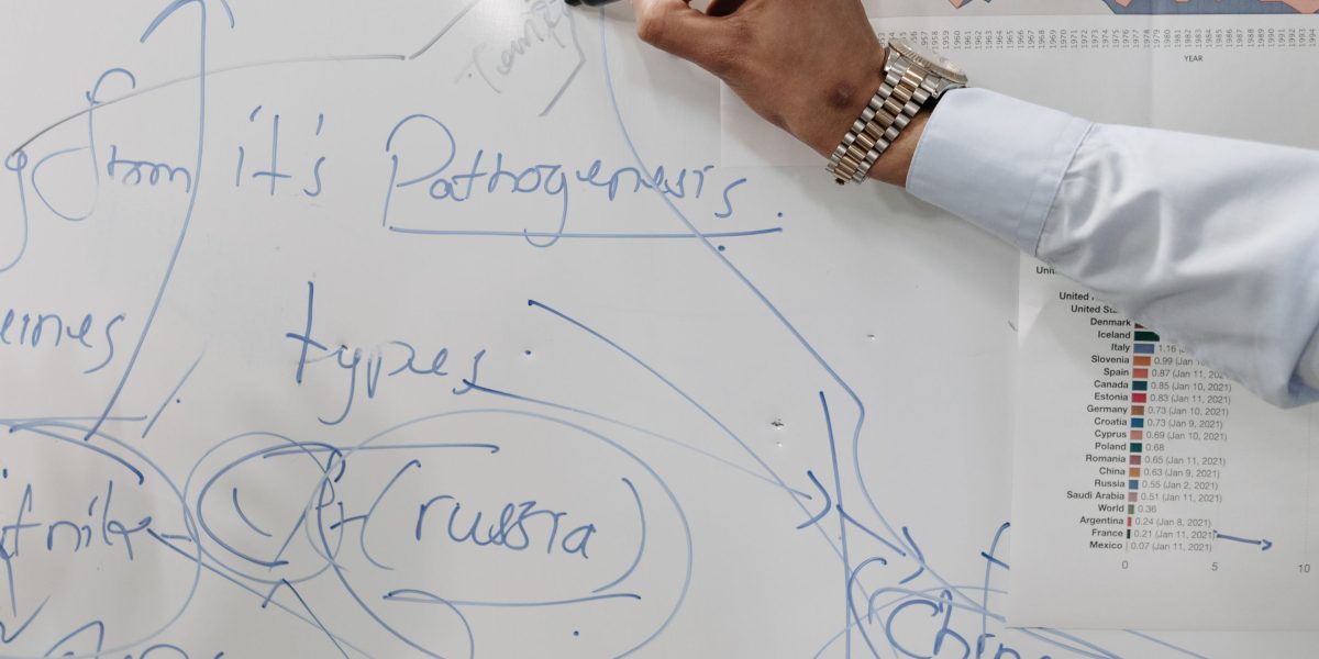 Professionals strategizing and outlining workflows on a whiteboard for new healthcare operational models.